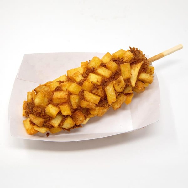 A Daddy Donut corn dog, covered in crispy french fries and brown sugar, on a white paper tray.