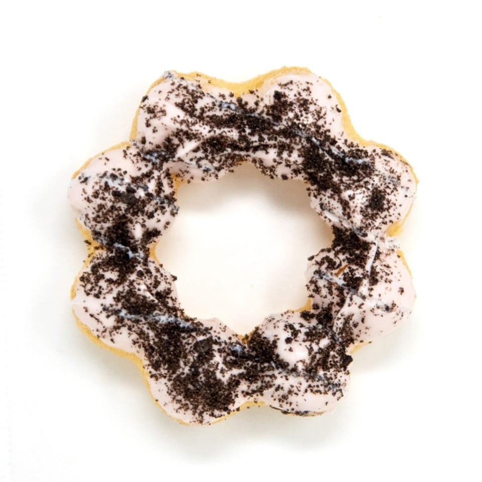 A star-shaped Daddy Donut with white icing and dark cookie crumbles on a white background.