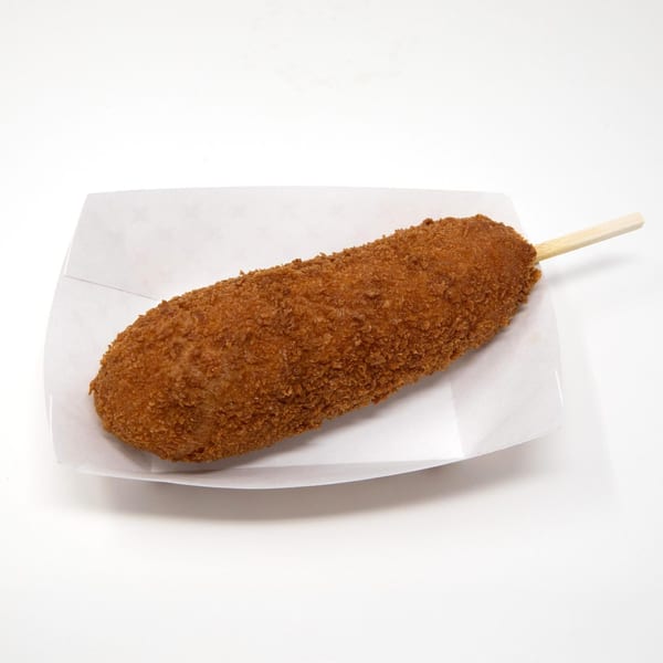 A Daddy Donut corn dog, golden brown and crispy, rests in a white paper tray.