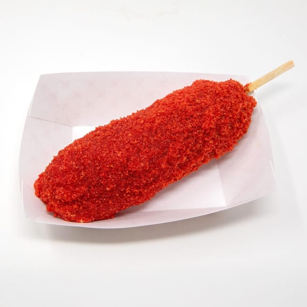A Daddy Donut corn dog, coated in bright red spicy seasoning, rests in a white paper tray.