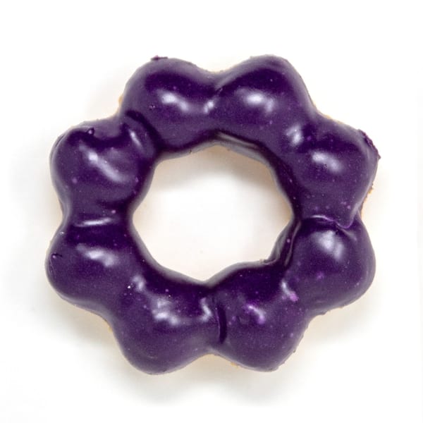 A Daddy Donut mochi donut with shiny purple ube glaze on a white background.