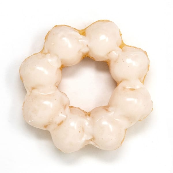A Daddy Donut mochi donut, light brown with a white glaze, on a white background.