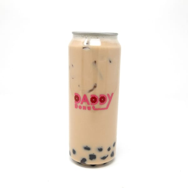Daddy Donut's iced milk tea with boba pearls in a clear can with a pink logo.