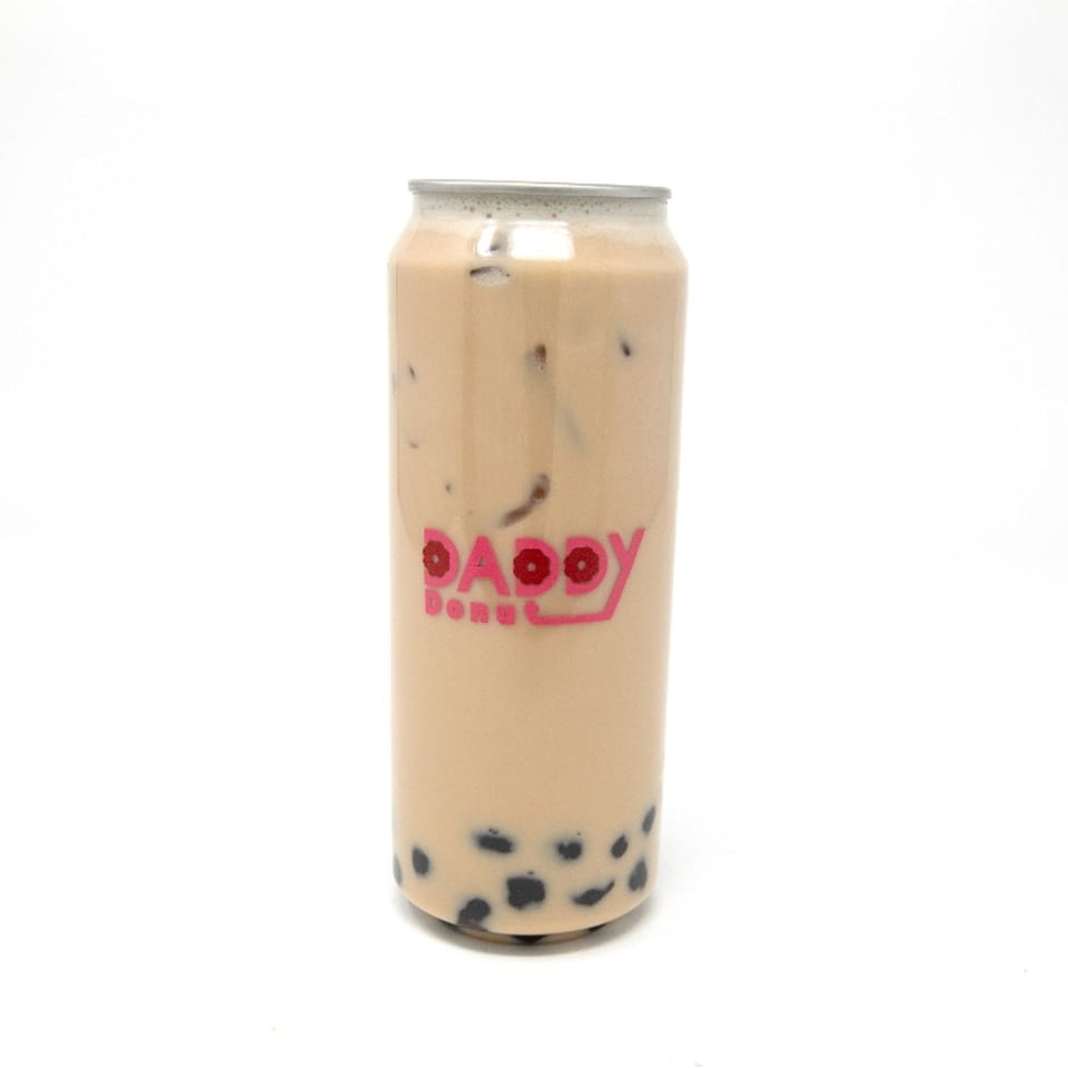 Daddy Donut's iced milk tea with boba pearls in a clear can with a pink logo.